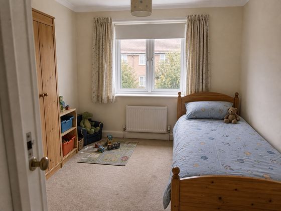 Plain small British child's bedroom with a single bed, radiator, uPVC window, toy storage and tired carpet before its makeover.